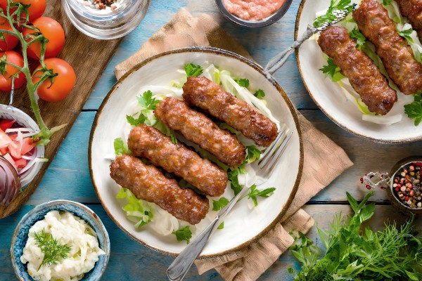 Ein traditionelles Balkangericht, Cevapi, serviert mit frischem Gemüse und Fladenbrot 