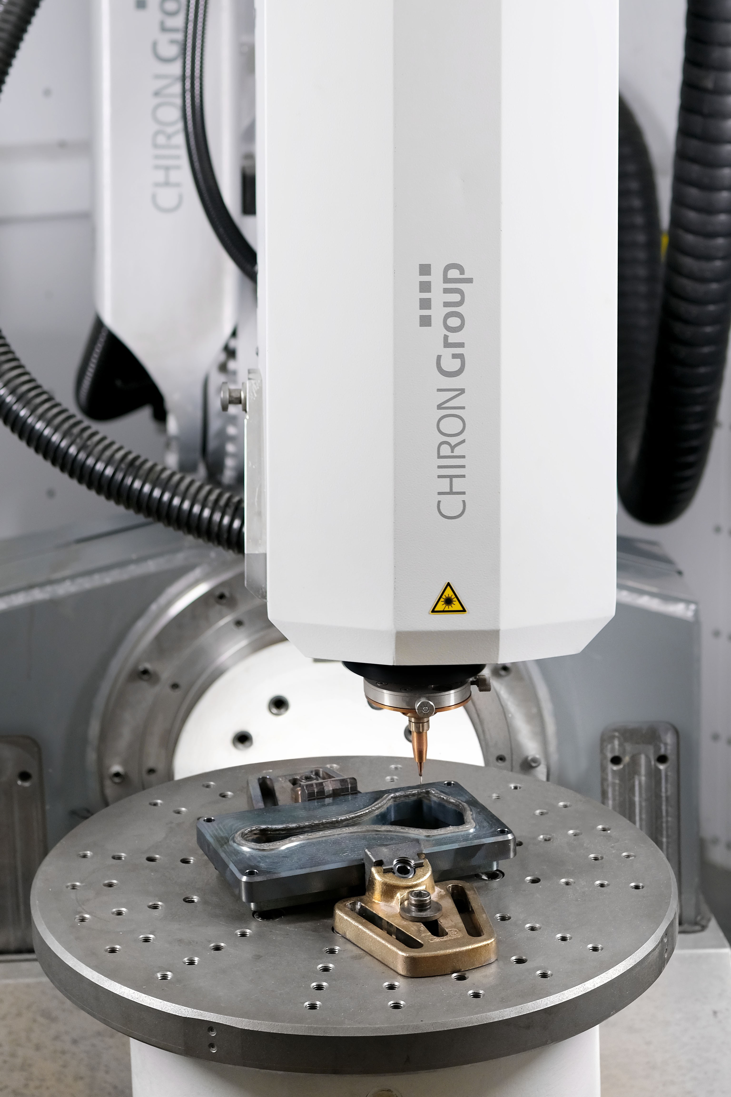 The working area of the AM Cube 3D metal printer with clamped trimming die of a car connecting rod that has been preheated to the processing temperature in the live demonstration.